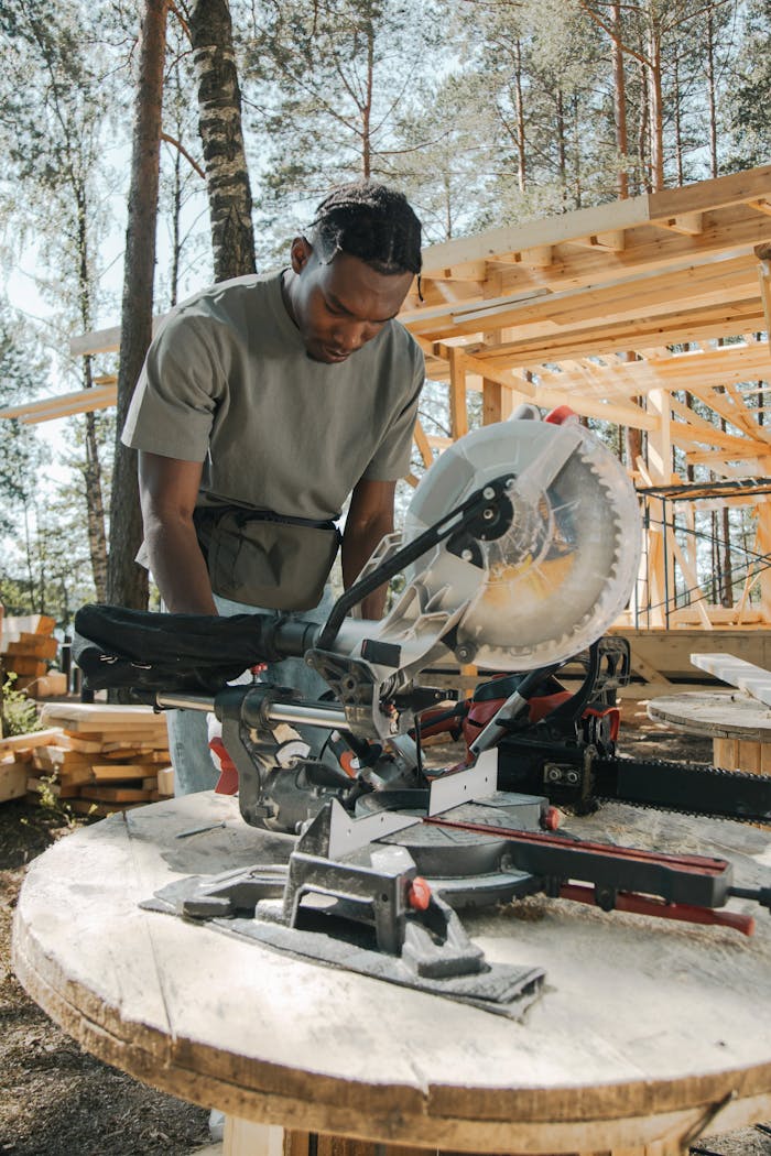 African American carpenter using a circular saw at an outdoor construction site.
